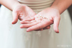 bride holding pearl earrings