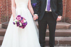 bride and groom holding hands purple pink white bouquet