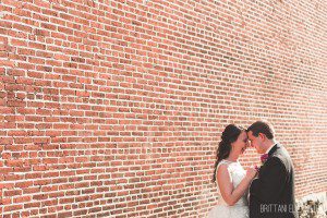 bride and groom in front of brick wall