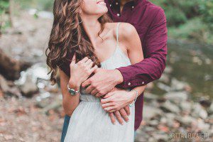 engaged couple embracing in woods