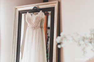 ivory lace beading wedding dress hanging up on mirror
