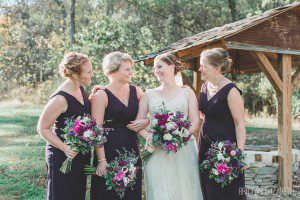 purple wedding bridesmaids and bride holding bouquets by water well