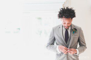 groom getting ready in gray suit plum tie