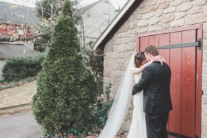 bride and groom nuzzling in front of stone building