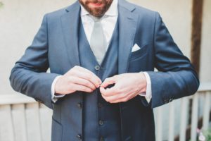 groom buttoning suit vest blue suit gray tie