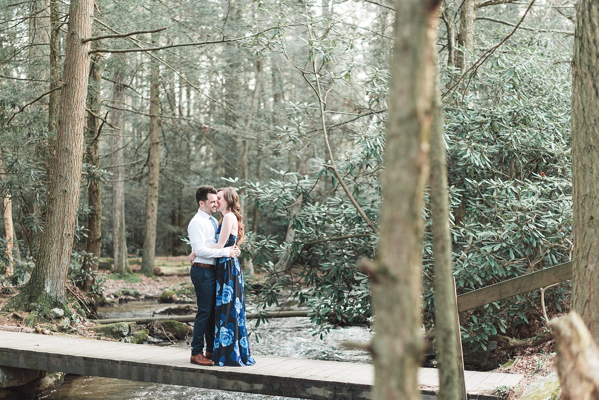 Couple embraces over a stream during outdoor engagement session in Pennsylvania