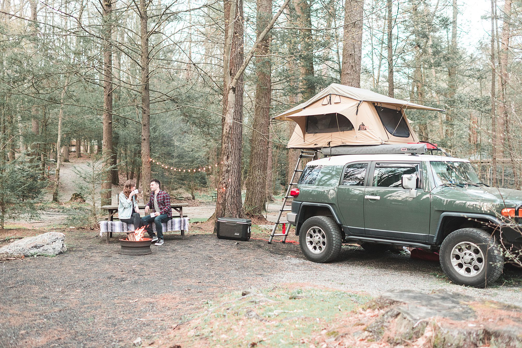 Tent on top of car campsite with string lights