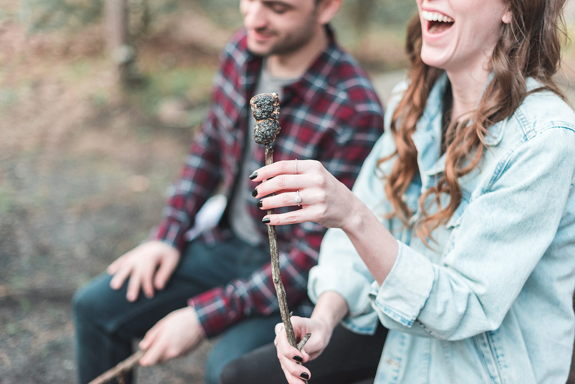 Couple laughs at burnt marshmallow during engagement session